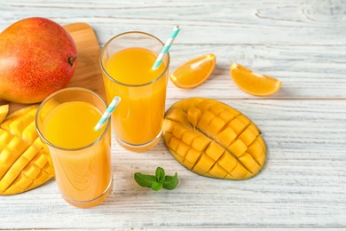 Tasty mango drink and fresh fruits on wooden table