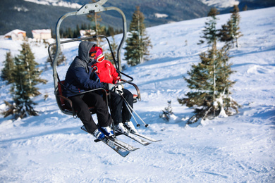 People using chairlift at mountain ski resort, space for text. Winter vacation