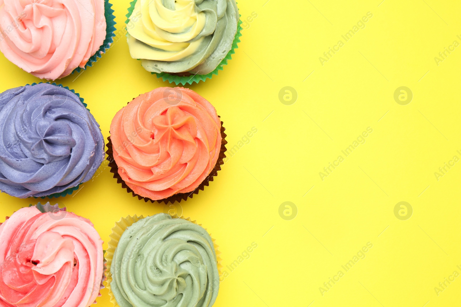 Photo of Delicious cupcake with bright cream on yellow background, flat lay. Space for text