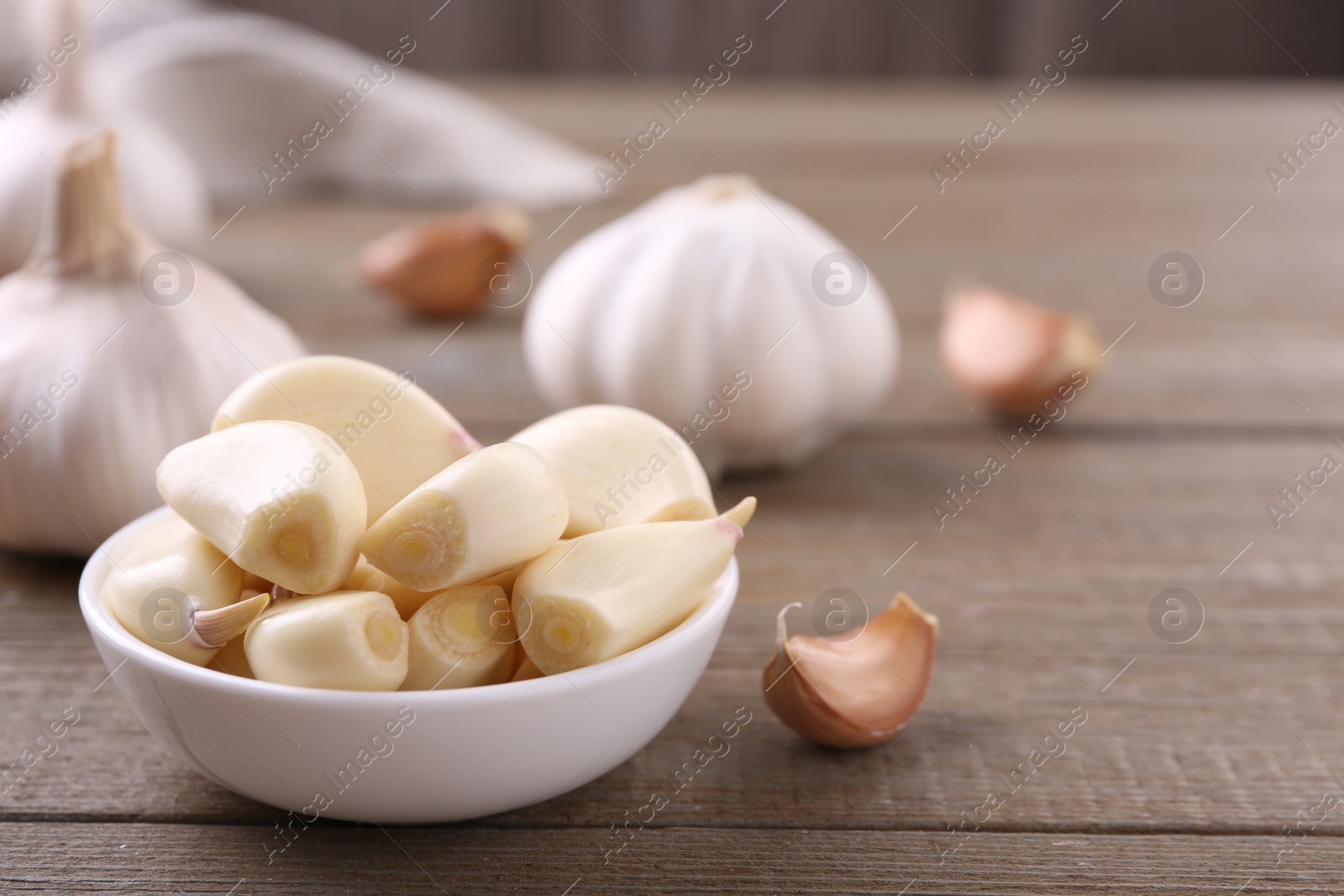 Photo of Aromatic garlic cloves and bulbs on wooden table, closeup. Space for text