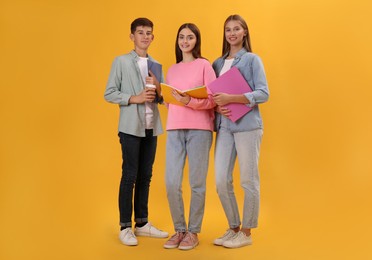 Group of teenage students with stationery on yellow background