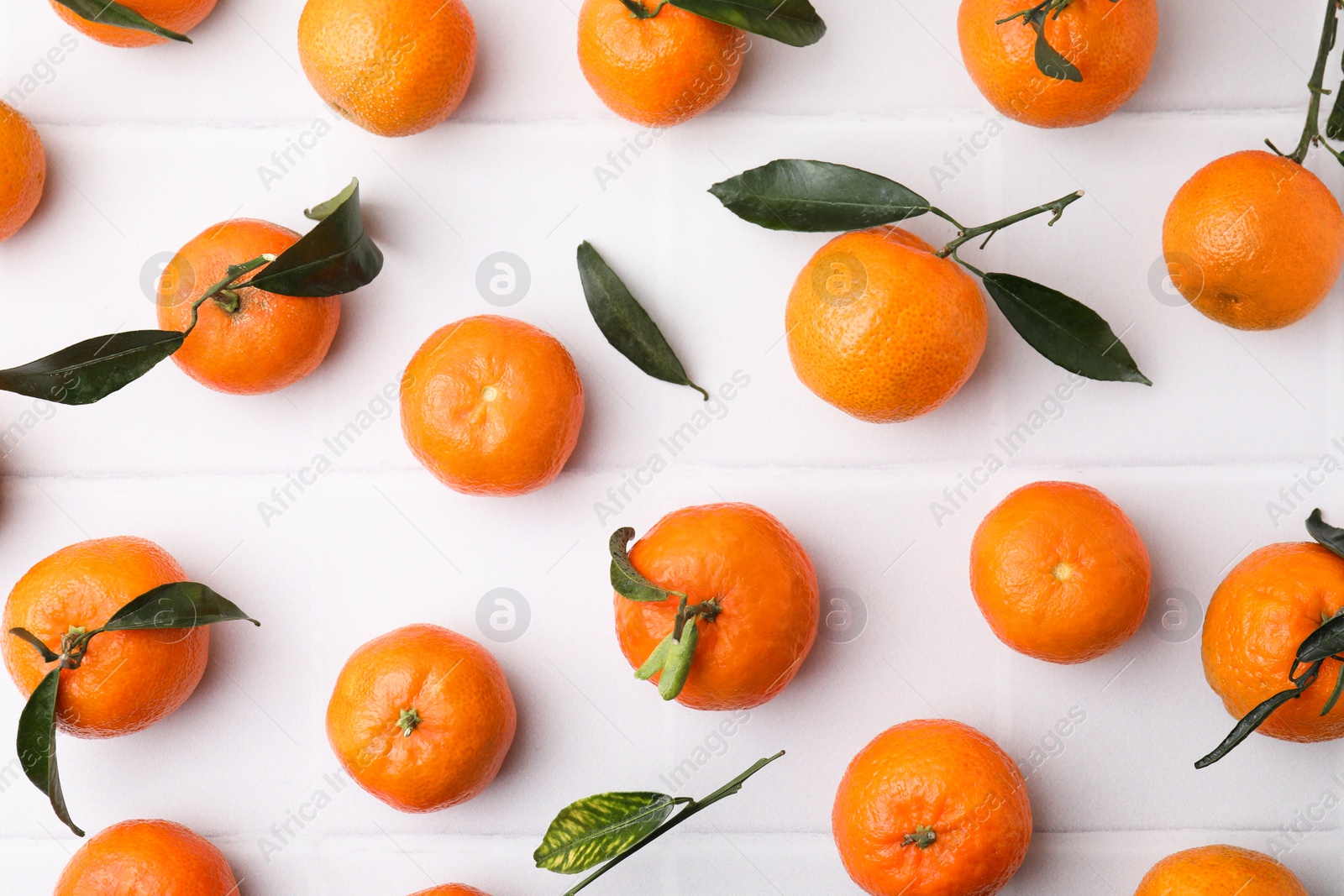 Photo of Fresh ripe tangerines with green leaves on white table, flat lay