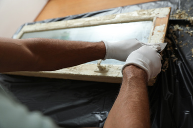 Photo of Man repairing old damaged window at table indoors, closeup