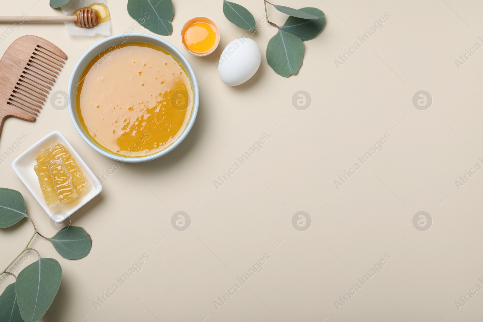 Photo of Homemade hair mask in bowl, ingredients and bamboo comb on beige background, flat lay. Space for text