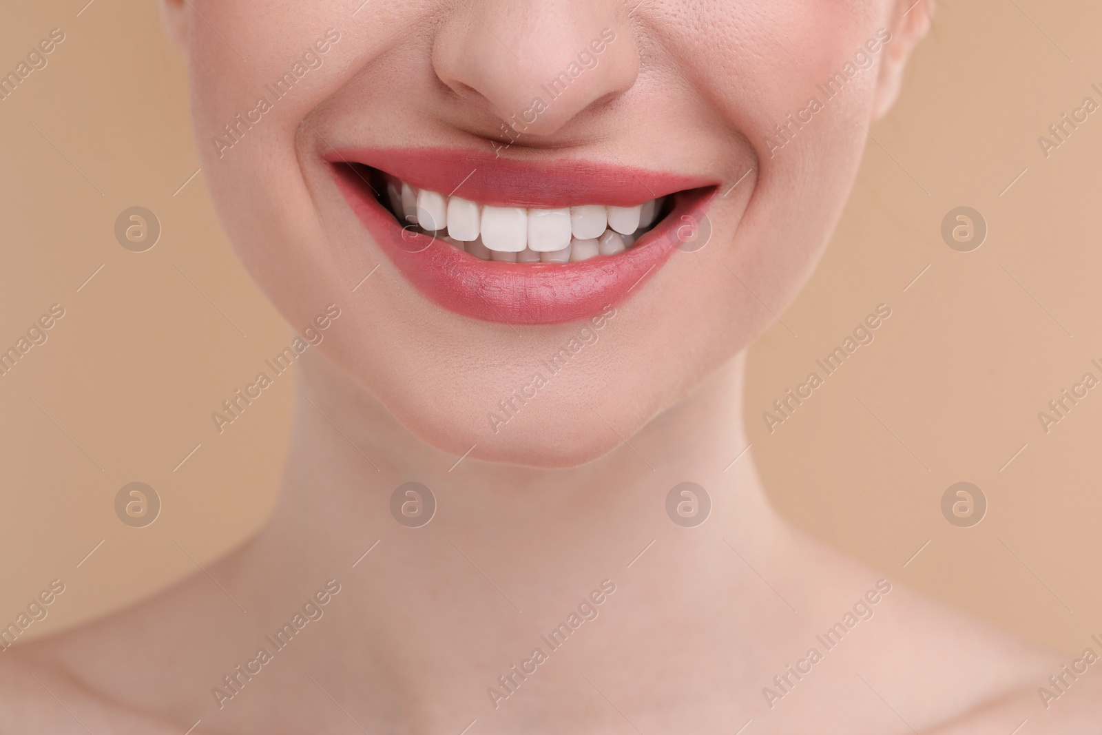 Photo of Young woman with beautiful smile on beige background, closeup