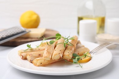 Photo of Plate with baked salsify roots and lemon on white table, closeup