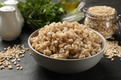 Photo of Tasty pearl barley porridge in bowl on dark table, closeup