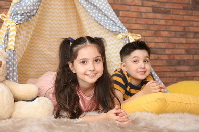 Photo of Playful little children in handmade tent indoors