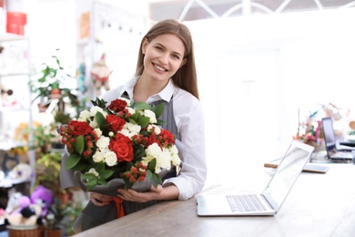 Photo of Female florist holding bouquet flowers at workplace