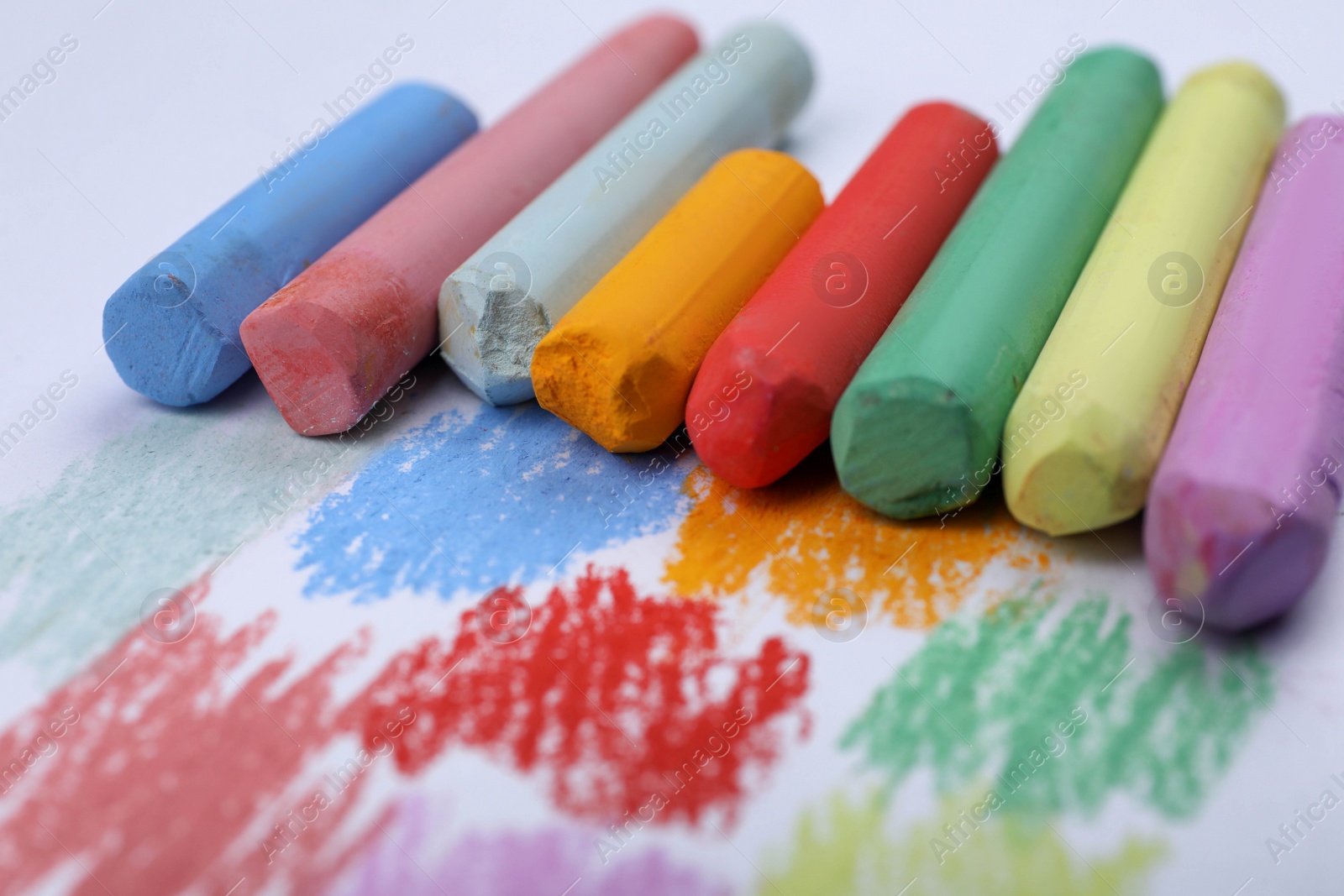 Photo of Colorful pastel chalks and scribbles on white background, closeup. Drawing materials