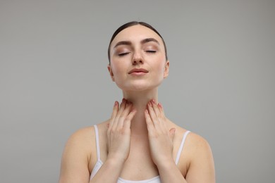 Photo of Beautiful woman touching her neck on grey background