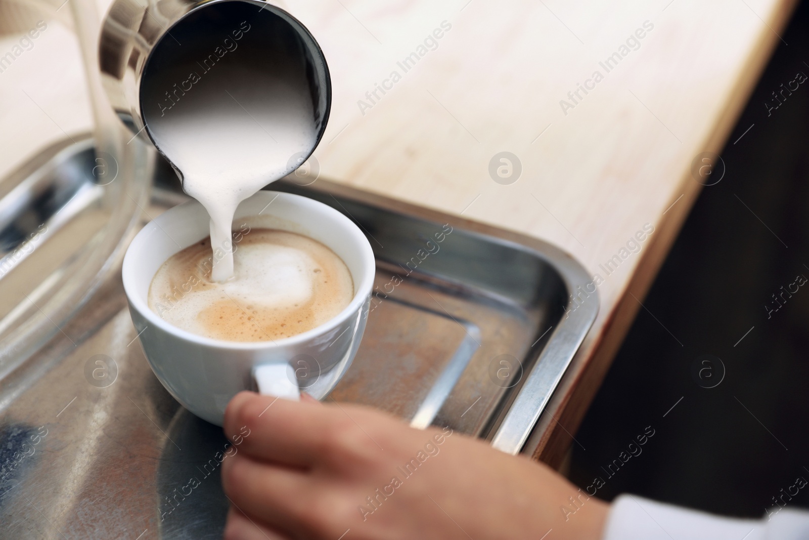 Photo of Barista adding milk to freshly brewed coffee on tray, closeup. Space for text