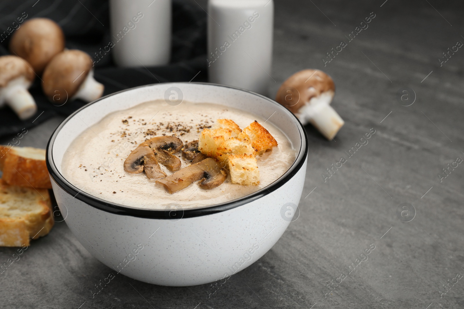 Photo of Delicious cream soup with mushrooms and croutons on black table