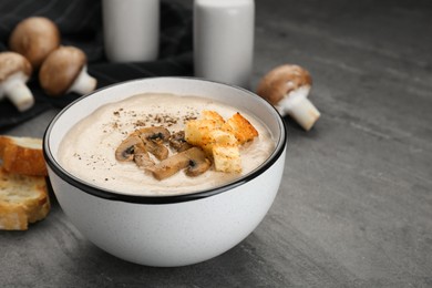 Photo of Delicious cream soup with mushrooms and croutons on black table