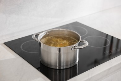 Pot with delicious soup on cooktop in kitchen