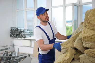 Construction worker with used glass wool in room prepared for renovation