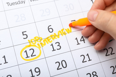 Photo of Woman marking date of job interview in calendar, closeup