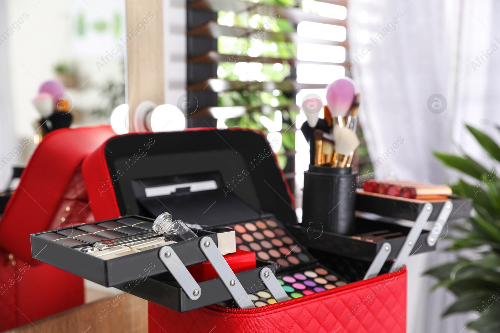 Photo of Beautician case with professional makeup products and tools on dressing table