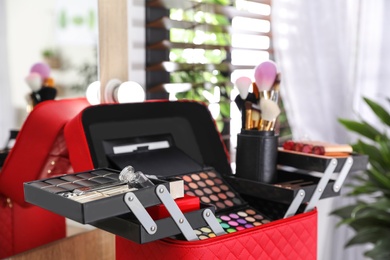 Beautician case with professional makeup products and tools on dressing table