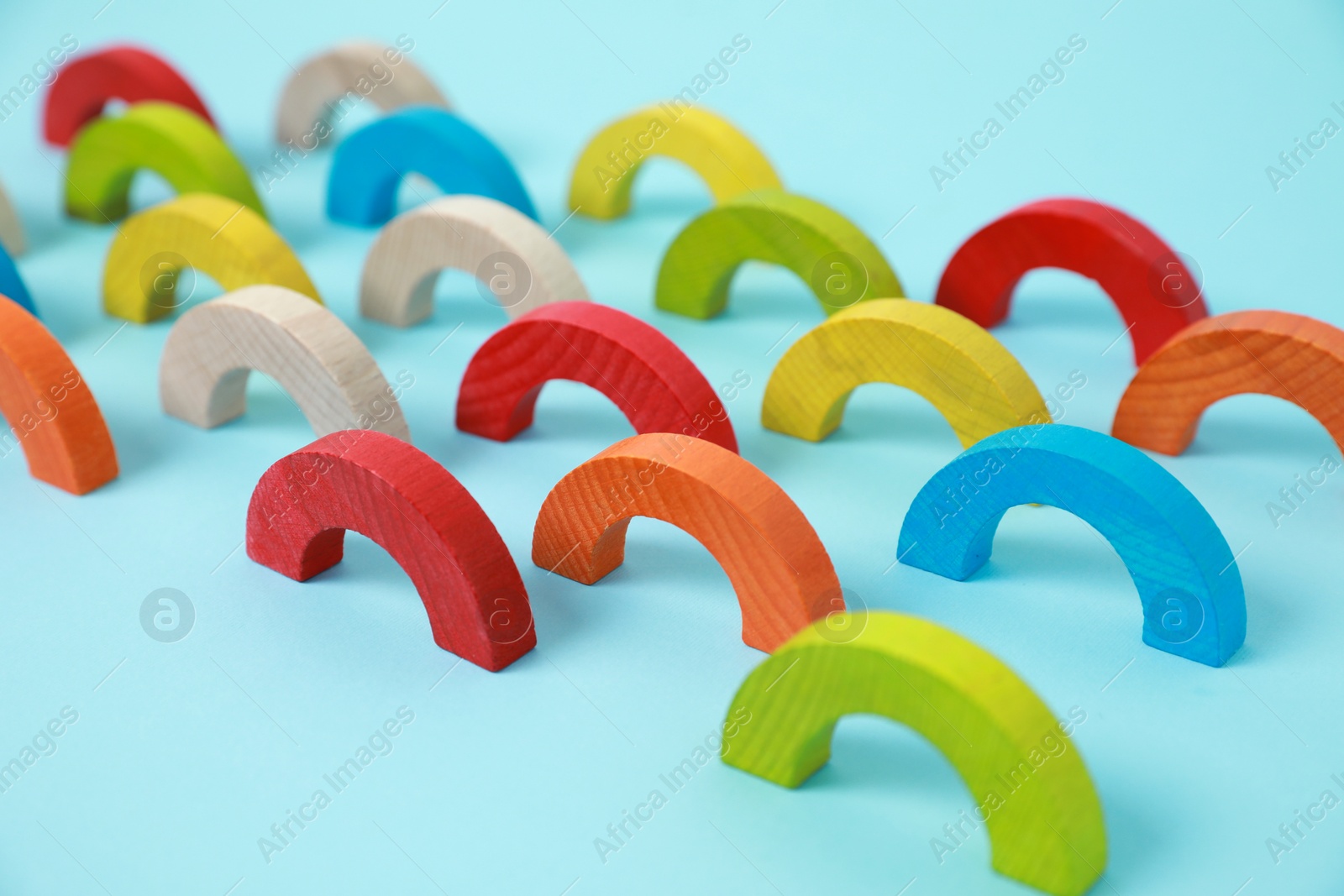 Photo of Colorful wooden pieces of playing set on light blue background. Educational toy for motor skills development