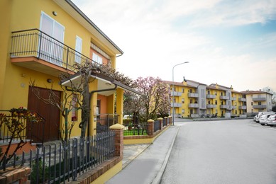 Photo of Suburban street with beautiful apartment buildings and blossoming trees on sunny spring day