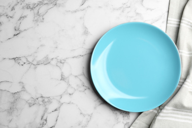 Photo of Light blue plate and fabric on white marble table, flat lay. Space for text