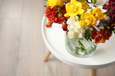Photo of Beautiful spring freesia flowers in vase on table, view from above. Space for text