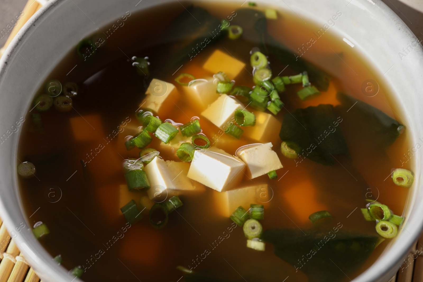 Photo of Bowl of delicious miso soup with tofu, closeup