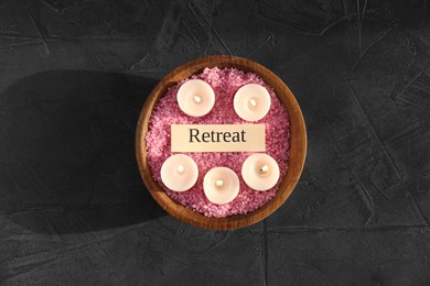 Photo of Retreat concept. Bowl with sea salt, card and burning candles on dark grey table, top view