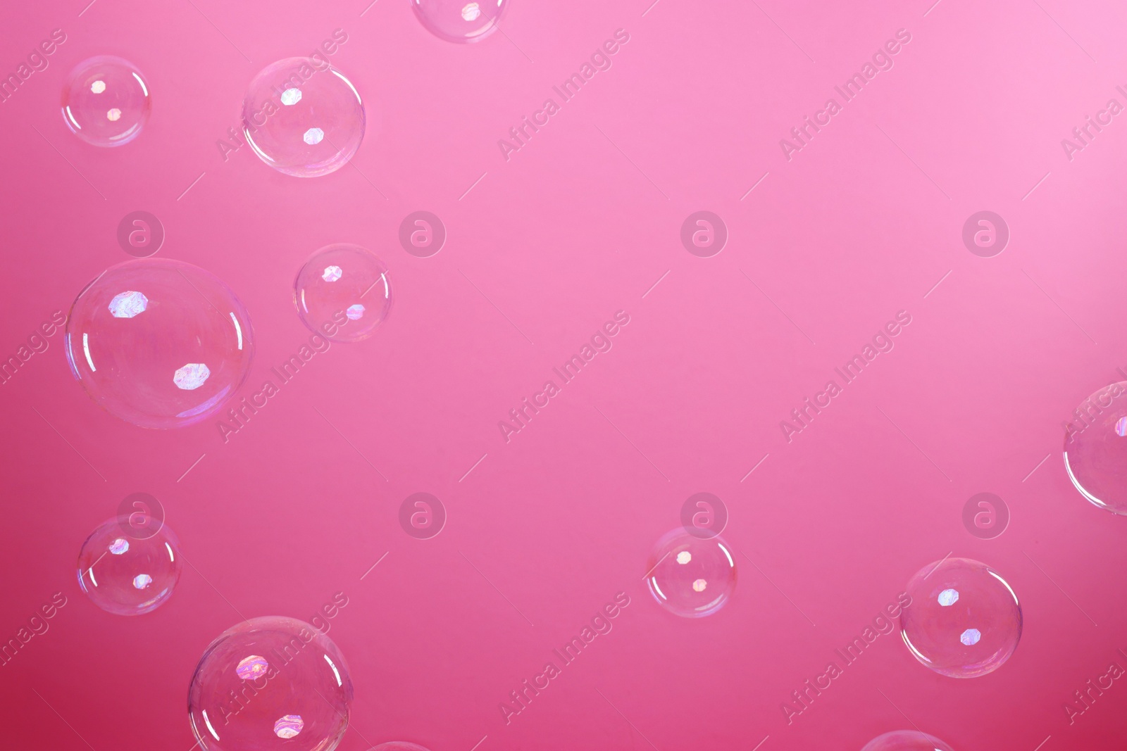 Photo of Many beautiful soap bubbles on pink background