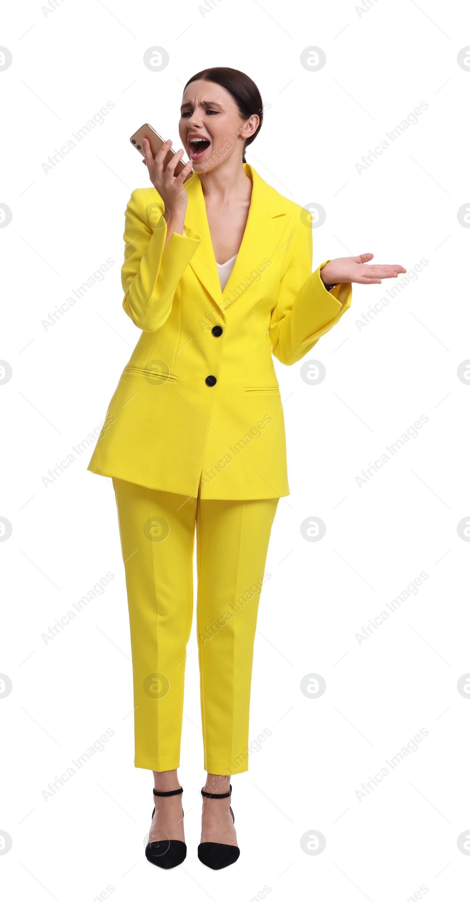 Photo of Beautiful emotional businesswoman in yellow suit using smartphone on white background