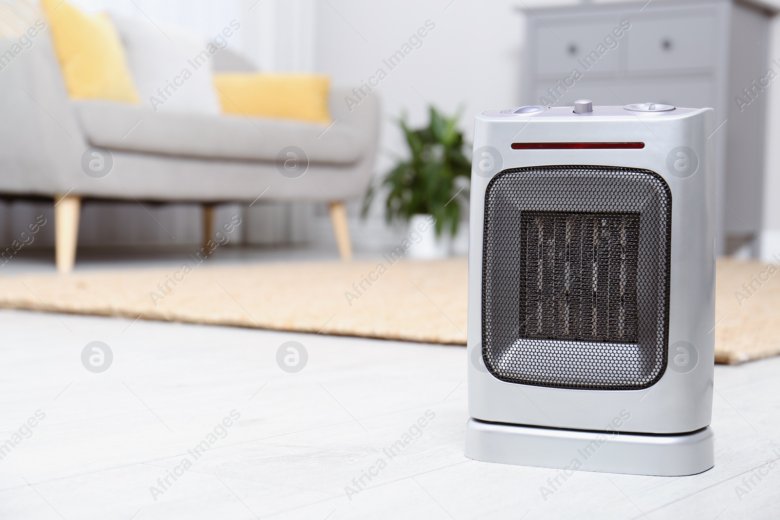 Photo of Modern electric fan heater on floor at home. Space for text