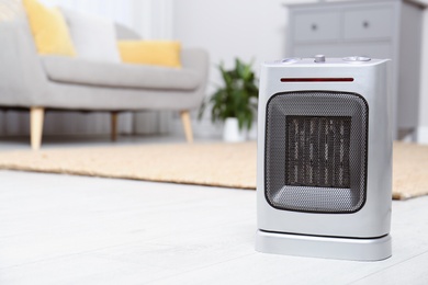 Modern electric fan heater on floor at home. Space for text