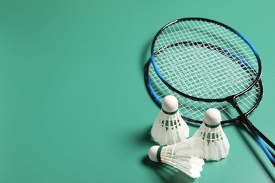 Photo of Feather badminton shuttlecocks and rackets on green background. Space for text