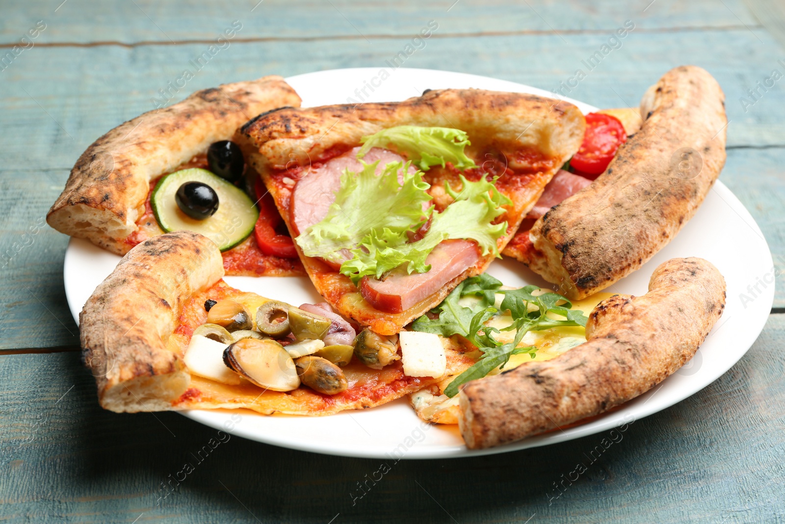 Photo of Slices of different delicious pizzas on blue wooden table