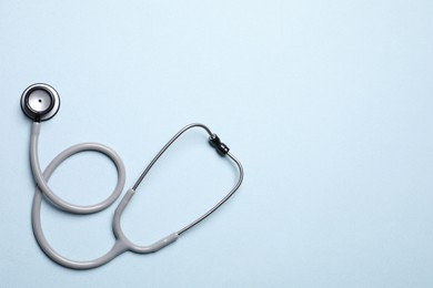 Photo of Stethoscope on light blue background, top view. Space for text