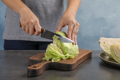 Photo of Woman cutting ripe cabbage at table, closeup