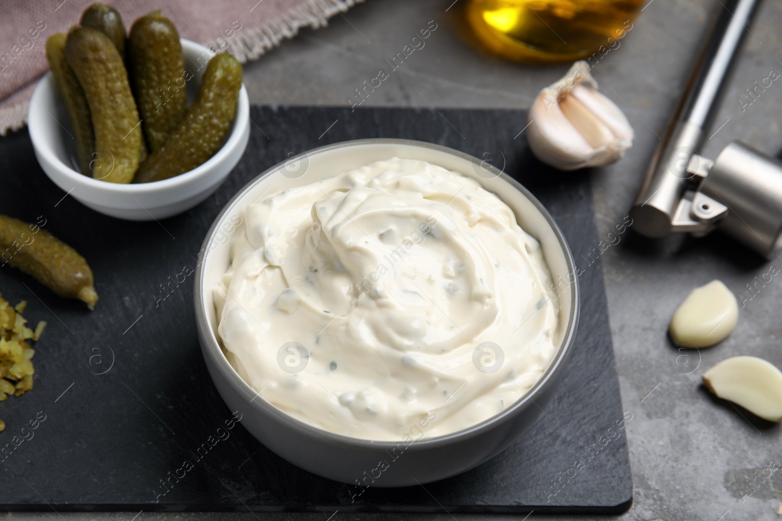 Photo of Tasty tartar sauce and ingredients on grey table