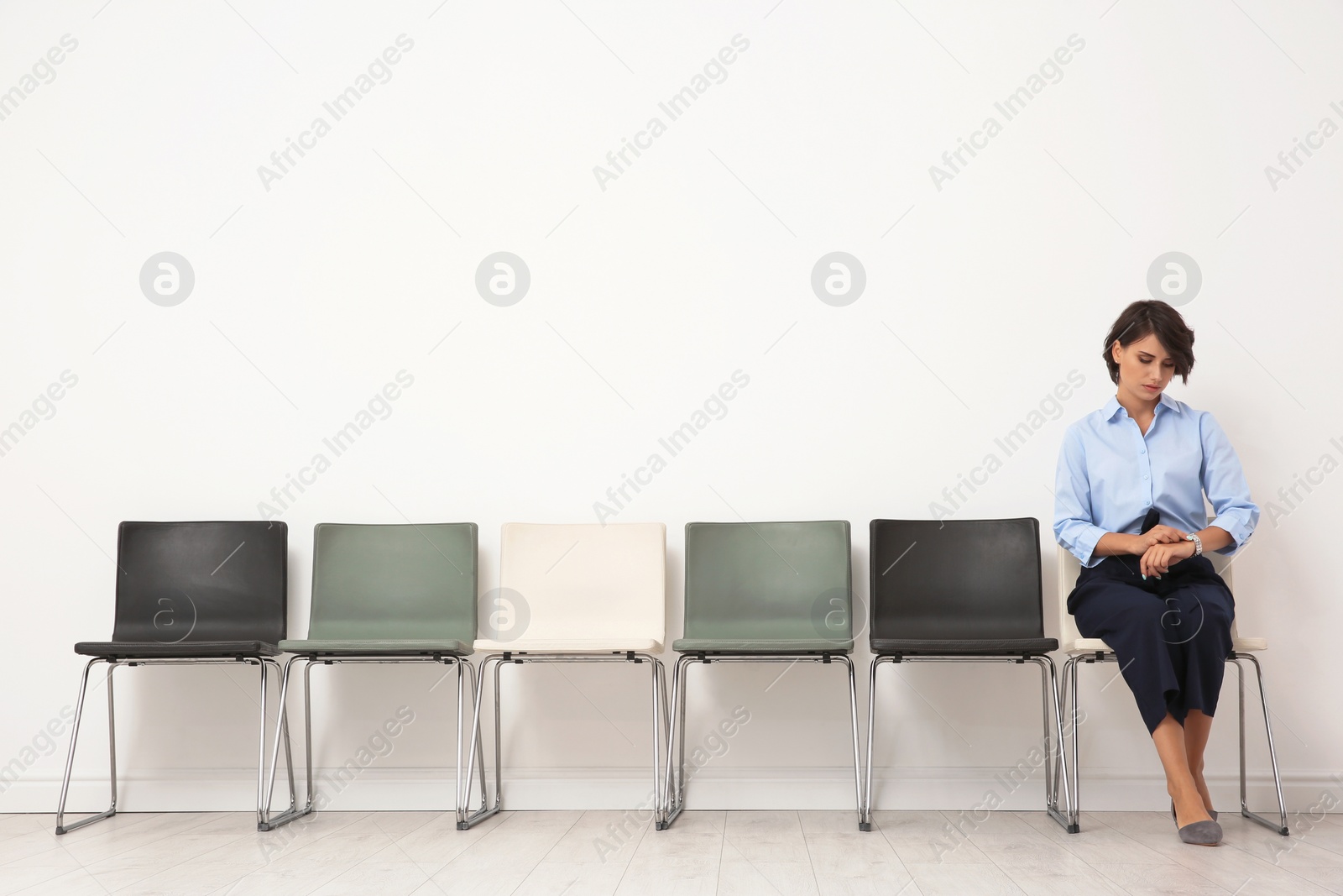 Photo of Young woman sitting on chair and waiting for job interview