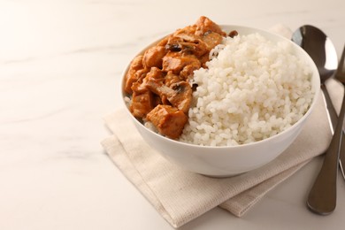 Bowl of delicious rice with meat and mushrooms on white marble table, space for text