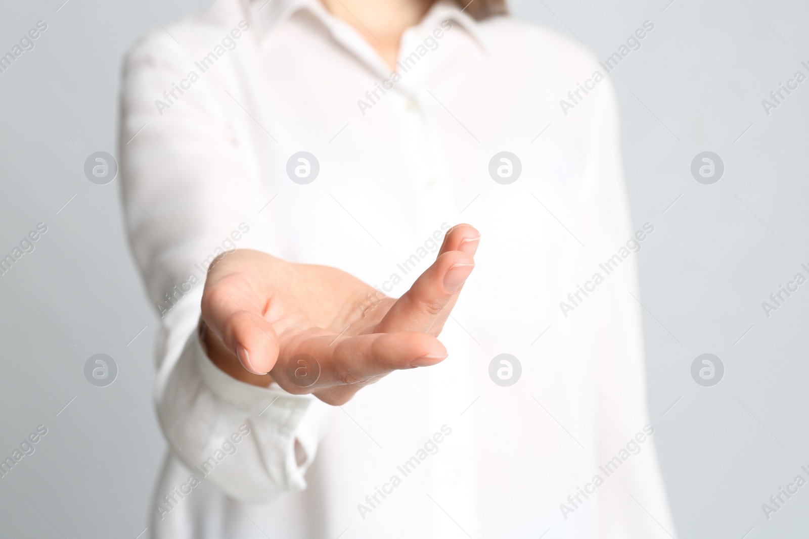 Photo of Young woman against light grey background, focus on hand