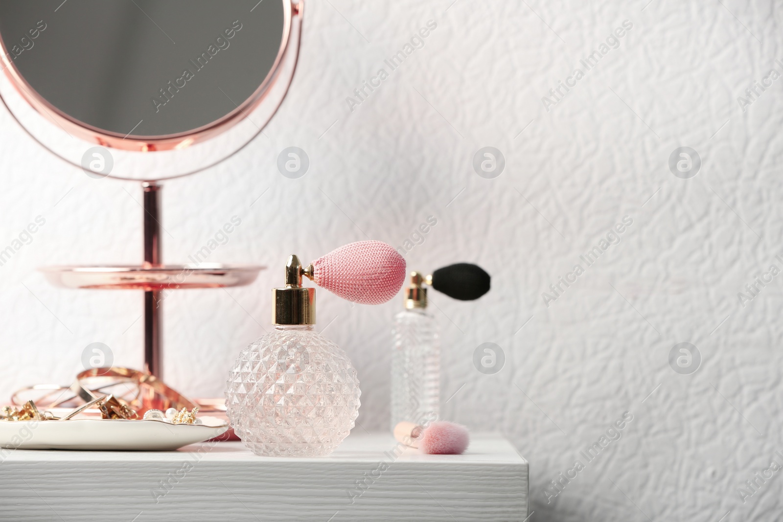 Photo of Perfume bottles and jewellery on dressing table. Space for text