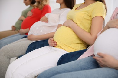 Photo of Group of pregnant women at courses for expectant mothers on blurred background, closeup