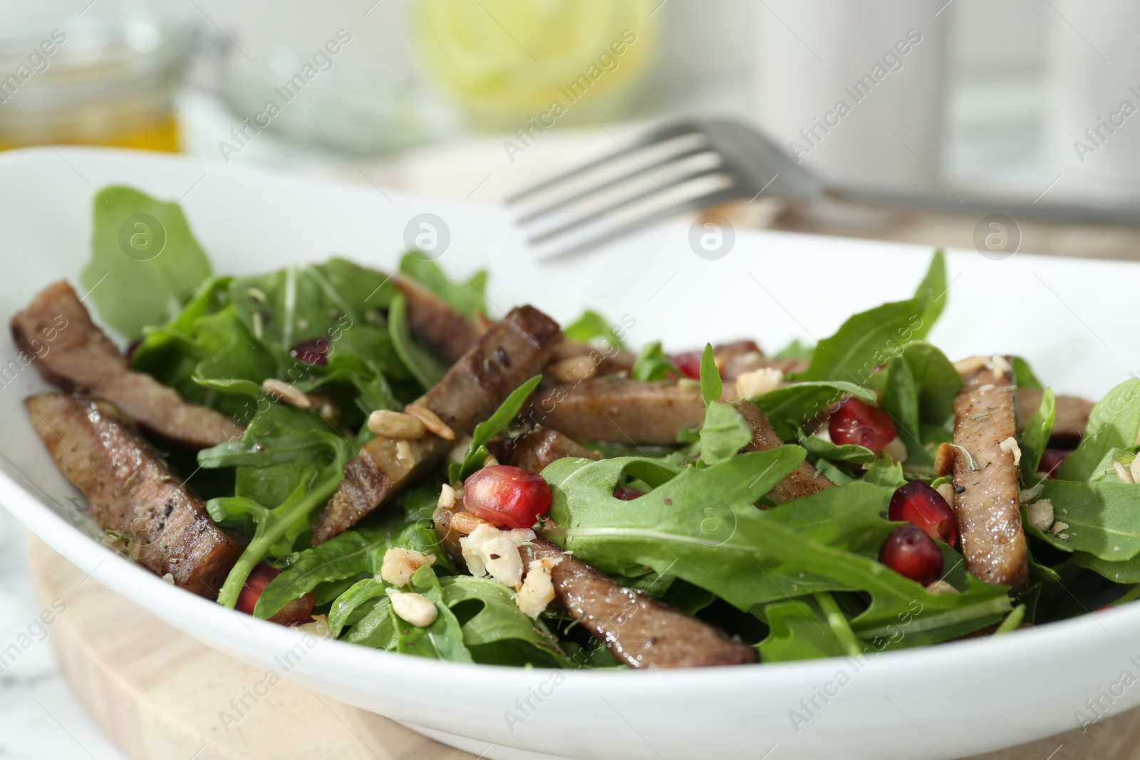 Photo of Delicious salad with beef tongue, arugula and seeds served on table, closeup
