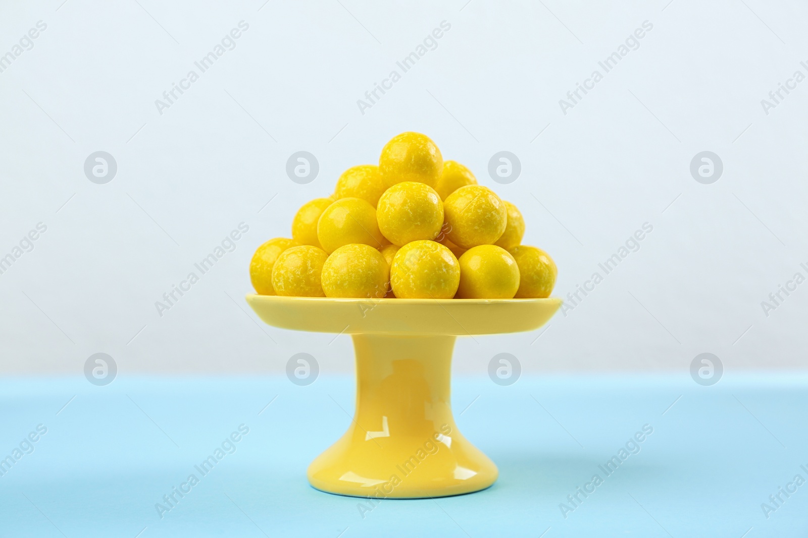 Photo of Delicious lemon chewing gums on light blue table