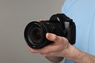 Photo of Photographer holding camera on grey background, closeup