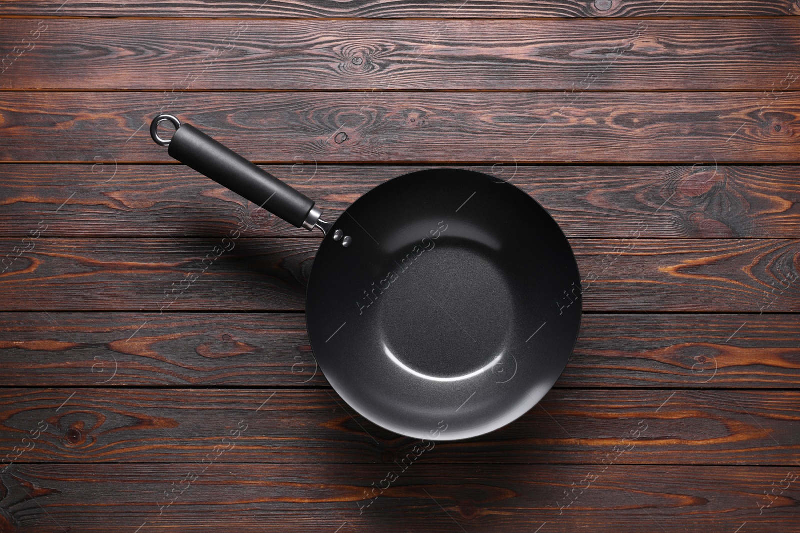 Photo of Empty iron wok on wooden table, top view. Chinese cookware