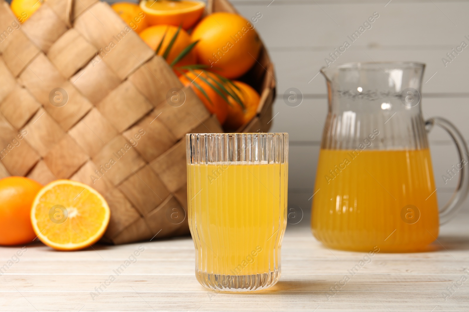 Photo of Tasty freshly made orange juice on white wooden table