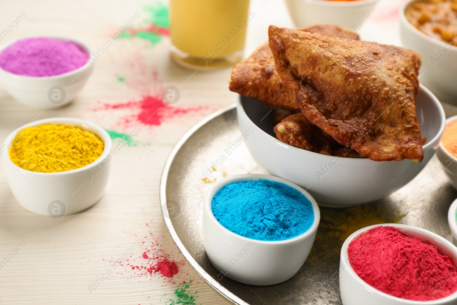 Photo of Traditional Indian food and color powders on white wooden table, closeup. Holi festival celebration