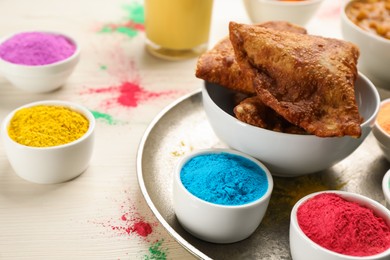 Traditional Indian food and color powders on white wooden table, closeup. Holi festival celebration